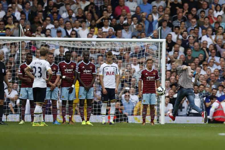 Un hincha que entr&oacute; a la cancha patea un tiro libre en un partido entre Tottenham y West Ham el s&aacute;bado, 16 de agosto de 2014, en Londres. (AP Photo/Sang Tan)