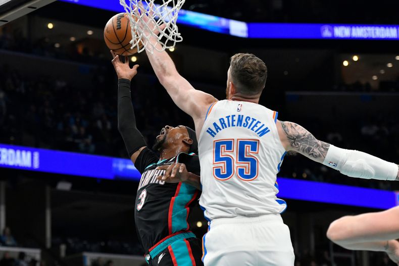 El base de los Grizzlies de Memphis, Kentavious Caldwell-Pope, izquierda, lanza a canasta ante el pívot del Thunder de Oklahoma City, Isaiah Hartenstein (55), en la primera mitad de un juego de baloncesto de la NBA el domingo 9 de noviembre de 2025, en Memphis, Tennessee. (Foto AP/Brandon Dill)