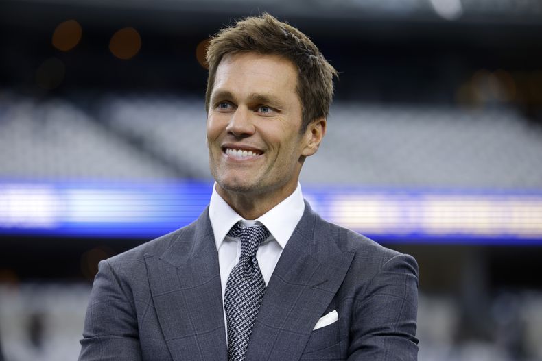 El analista principal de la NFL de Fox Sports, Tom Brady, sonríe en el campo durante los calentamientos antes de un partido de fútbol americano de la NFL entre los Lions de Detroit y los Cowboys de Dallas en Arlington, Texas, el domingo 13 de octubre de 2024. (AP Foto/Gareth Patterson)