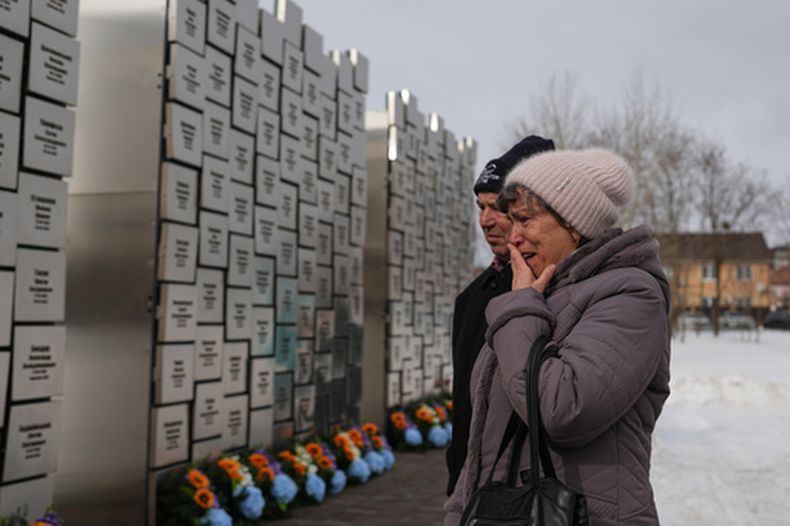 Parientes de personas fallecidas durante la ocupación rusa reaccionan en el Muro de Recuerdo durante una ceremonia para conmemorar el cuarto aniversario de la invasión rusa de plena escala de Ucrania, en Bucha, Ucrania, el martes 24 de febrero de 2026. (AP Foto/Sergei Grits)