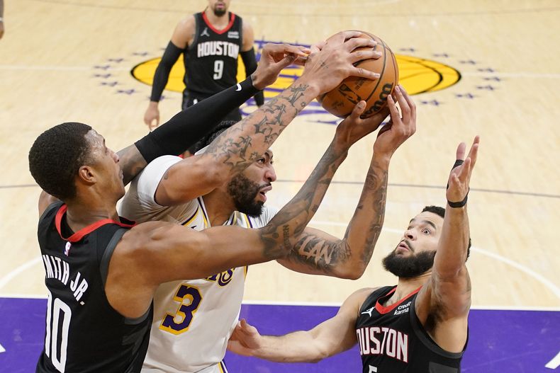 El jugador de los Lakers de Los Ángeles Anthony Davis, en el centro, arrebata un rebote al jugador de los Rockets de Houston Jabari Smith Jr., a la izquierda, y Fred VanVleet durante la primera mitad de su juego de NBA el sábado 2 de diciembre de 2023 en Los Ángeles. (AP Foto/Mark J. Terrill)