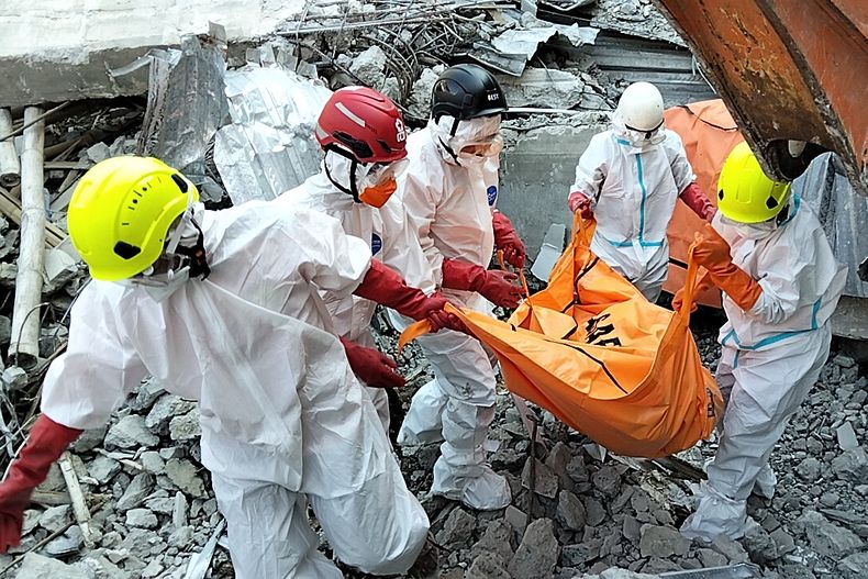 En esta imagen difundida por la Agencia Nacional de Búsqueda y Rescate de Indonesia (BASARNAS) el lunes 6 de octubre de 2025, se puede ver a rescatistas mientras retiran el cuerpo de una víctima entre los escombros de un edificio colapsado dentro de una escuela islámica en Sidoarjo, en Java Oriental, Indonesia. (BASARNAS vía AP)