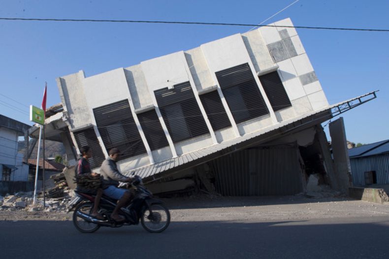 Motoristas pasan junto a un edificio que se vino abajo durante un sismo en Reo, en la provincia de Nusa Tenggara Oriental, Indonesia, el lunes 17 de agosto de 2026. (AP Foto/Firdia Lisnawati)