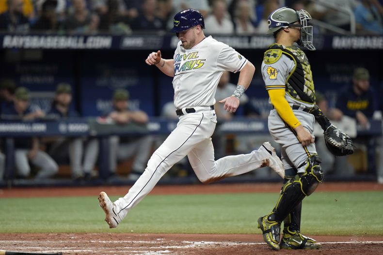 Luke Raley, de los Rays de Tampa Bay, anota mientras el receptor de los Cerveceros de Milwaukee, William Contreras (24), observa en un elevado de sacrificio de Francisco Mejia durante la octava entrada del juego de béisbol el viernes 19 de mayo de 2023, en San Petersburgo, Florida. (AP Foto/Chris OMeara)