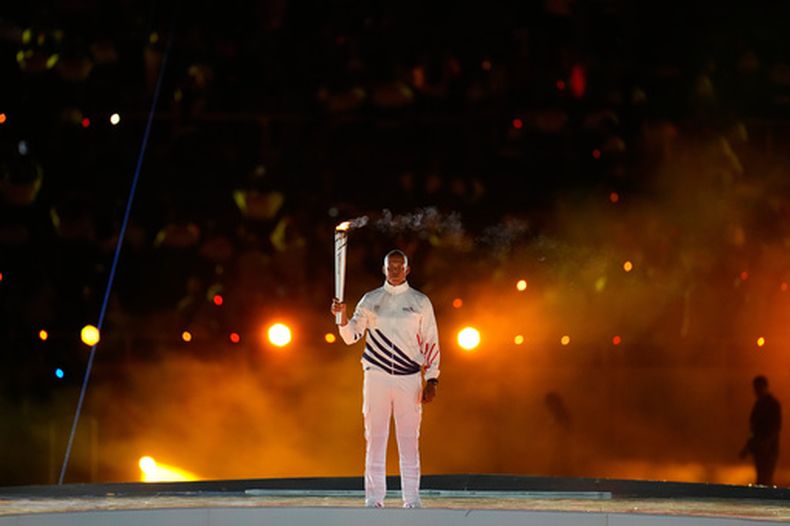 El exatleta Félix Sánchez sostiene la antorcha en la ceremonia inaugural de los Juegos Centroamericanos y del Caribe en Santo Domingo, el viernes 24 de julio de 2026 (AP Foto/Fernando Vergara)