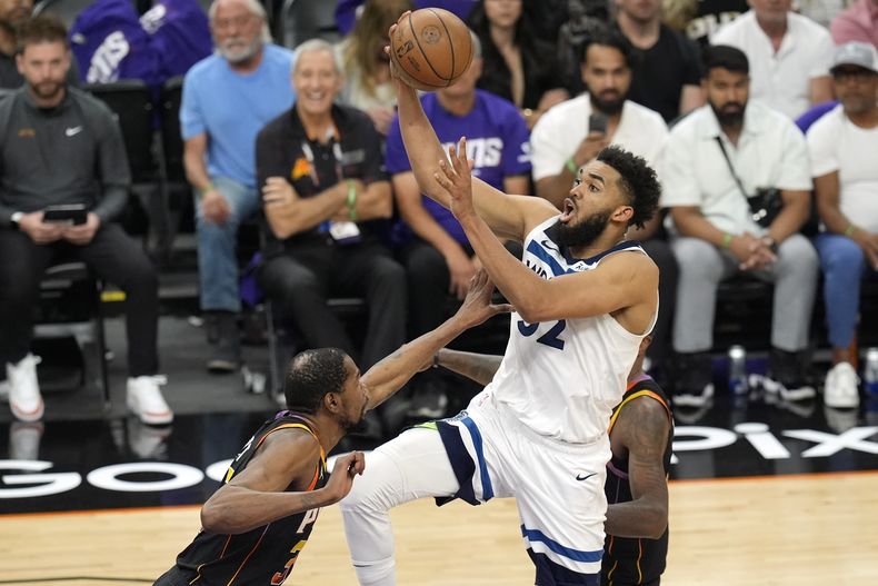 El pívot de los Timberwolves de Minnesota Karl-Anthony Towns avanza con el balón hacia la canasta mientras lo defiende Kevin Durant de los Suns de Phoenix en el juego 4 de la serie de primera ronda de la postemporada el domingo 28 d abril del 2024. (AP Foto/Ross D. Franklin)
