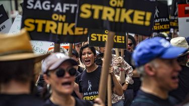 Guionistas y actores en huelga gritan consignas mientras caminan en un plantón el viernes 14 de julio de 2023, en NBC Universal Studios en Nueva York. (Foto AP/Bebeto Matthews)