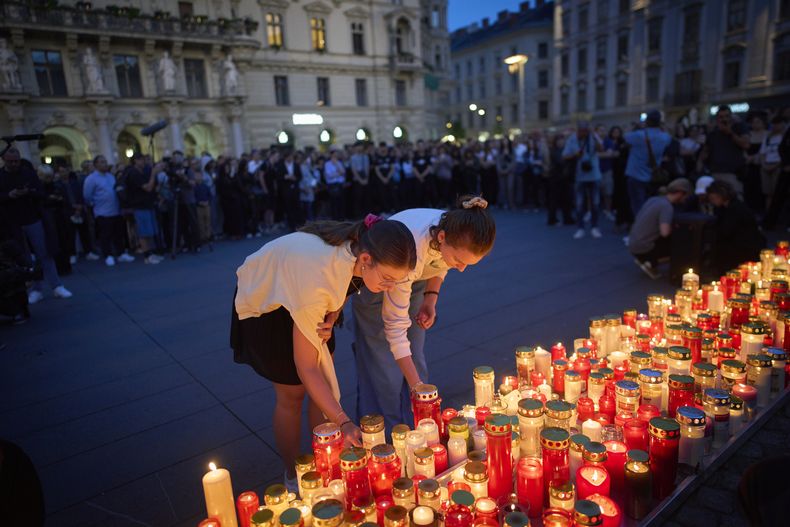 Gente enciende velas por las víctimas de un antiguo alumno que hizo disparos en una escuela, donde mató a 10 personas e hirió a muchas otras antes de suicidarse, en Graz, Austria, el martes 10 de junio de 2025. (AP Foto/Darko Bandic)