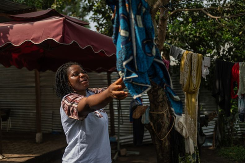 Esther Lutula, una mujer de 26 años que tiene cuatro meses de embarazo y madre de cuatro hijos, que dejó de asistir a las revisiones prenatales debido al brote de ébola, hace la colada delante de su casa en Bunia, en el nordeste de República Democrática del Congo, el martes 16 de junio de 2026. (AP Foto/Moses Sawasawa)