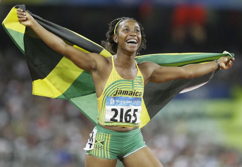 ARCHIVO - Shelly-Ann Fraser celebra con la bandera de Jamaica tras ganar los 100 metros femeninos de los Juegos Olímpicos de Beijing, el 17 de agosto de 2008. (AP Foto/Anja Niedringhaus)