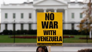 Una manifestante sostiene un cartel durante una protesta frente a la Casa Blanca en Washington, el sábado 15 de noviembre de 2025. (AP Foto/José Luis Magana)