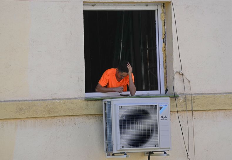 Un trabajador mira su celular durante un descanso junto a un aparato recién instalado de aire acondicionado en el exterior de un apartamento en Madrid, España, el miércoles 26 de abril de 2023. La mayor parte de España enfrentaba el jueves 27 de abril de 2023 un aumento de las temperaturas con “valores propios del verano” que podrían llegar a los 38 grados Celsius (100 grados Fahrenheit) en el sureño Valle del Guadalquivir. (AP Foto/Paul White)