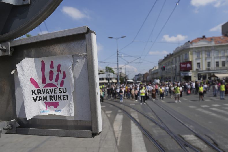 Una calcomanía con la frase Tienes sangre en las manos se encuentra pegada en un señalamiento vial al momento en que estudiantes universitarios realizan una marcha silenciosa en honor a las 16 personas que murieron aplastadas por un dosel de concreto que colapsó el 1 de noviembre en una estación de tren en Novi Sad y para exigir una elección inmediata tras meses de protestas anticorrupción, en Belgrado, Serbia, el martes 6 de mayo de 2025. (AP Foto/Darko Vojinovic)