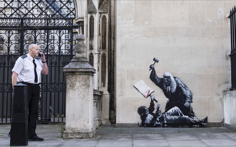 Fotografía sin fecha publicada por Banksy de la nueva obra de arte del artista que retrata a un juez golpeando a un manifestante con un mazo en los Tribunales Reales de Justicia de Londres. (Banksy via AP)