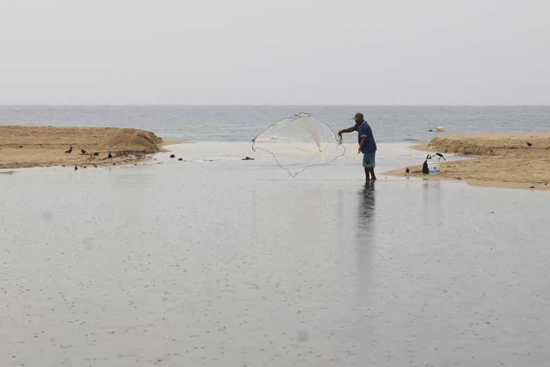 Un pescador arroja su red antes de la llegada del huracán Erick, el miércoles 18 de junio de 2025, en Puerto Escondido, en el estado de Oaxaca, en el sur de México. (AP Foto/Luis Alberto Cruz)