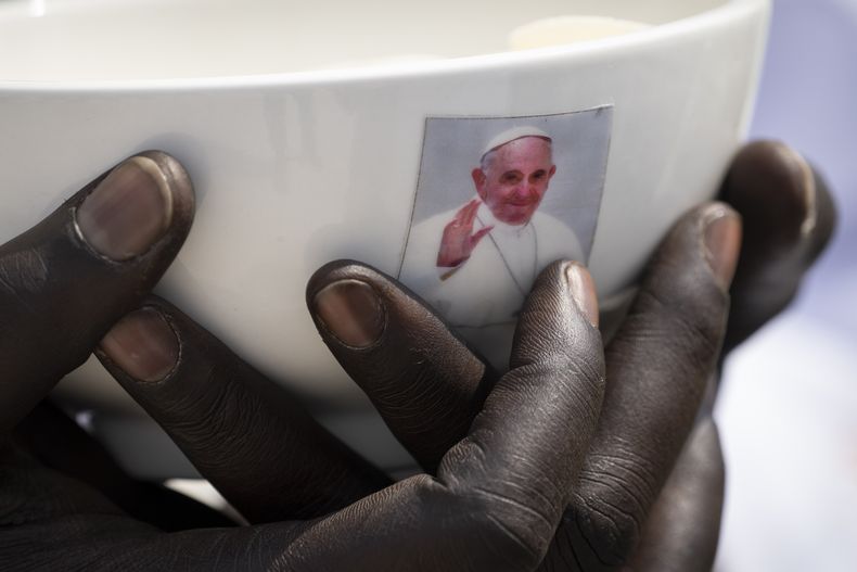 ARCHIVO - Un sacerdote sostiene un cuenco con una fotografía del papa Francisco durante una misa en el mausoleo John Garang en Yuba, Sudán del Sur, el 5 de febrero de 2023. (AP Foto/Ben Curtis, archivo)