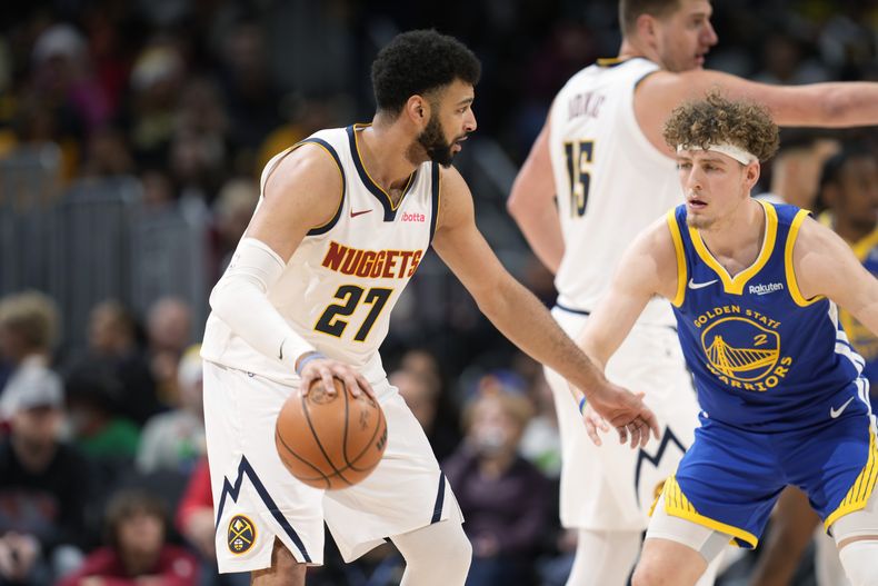 El base de los Nuggets de Denver Jamal Murray avanza con el balón hacia la canasta mientras lo defiende el base de los Warriors de Golden State Brandin Podziemski en el encuentro del lunes 25 de diciembre del 2023. (AP Foto/David Zalubowski)