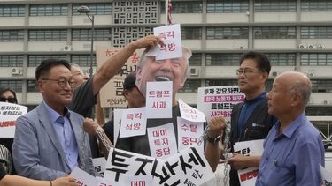 Manifestantes colocan pegatinas a una persona que lleva una máscara del presidente de Estados Unidos, Donald Trump, durante una manifestación contra la detención de trabajadores surcoreanos en Georgia, cerca de la embajada de Estados Unidos en Seúl, Corea del Sur, el martes 9 de septiembre de 2025. Los carteles dicen Liberación inmediata y disculpa de Trump. (AP Foto/Ahn Young-joon)