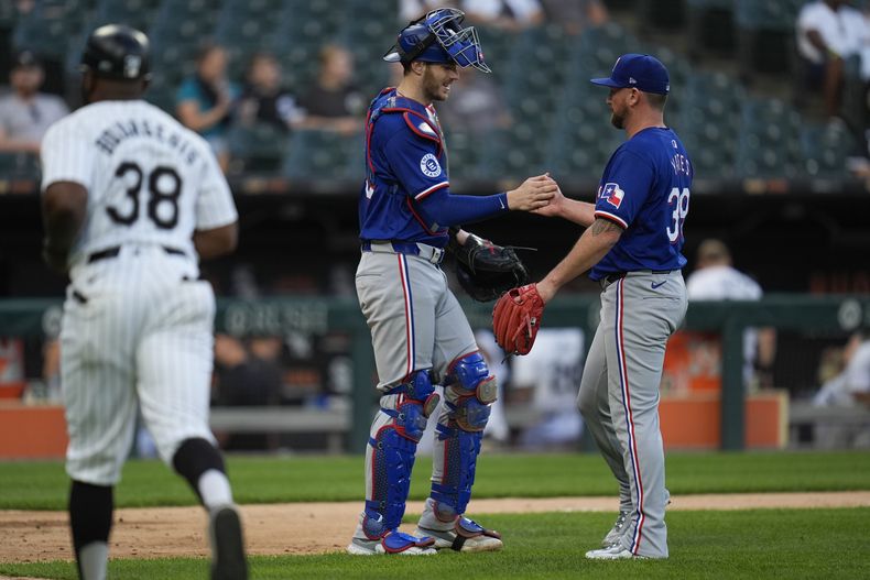El lanzador de los Rangers de Texas, Kirby Yates, a la derecha, y el receptor Jonah Heim celebran la victoria de su equipo por 3-1 sobre los Medias Blancas de Chicago en el primer juego de una doble cartelera de béisbol, el miércoles 28 de agosto de 2024, en Chicago. (AP Foto/Erin Hooley)