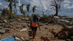 Una mujer y su perro caminan entre las ruinas de las casas destruidas por el huracán Melissa en Boca de dos Ríos, Cuba, el jueves 30 de octubre de 2025. (Foto AP/Ramón Espinosa)