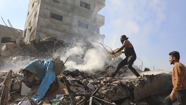 Palestinos sofocn las llamas sobre los escombros de edificios destruidos por el bombardeo israelí de la Franja de Gaza en el campamento de refugiados Nusseirat, 17 de noviembre de 2023. (AP Foto/Marwan Saleh)