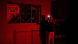 ARCHIVO - Una mujer sostiene en alto la linterna de su celular mientras habla con una amiga durante un apagón programado como parte del racionamiento de electricidad en Santa Cruz del Norte, que alberga una de las mayores centrales termoeléctricas de Cuba, el 3 de febrero de 2026. (AP Foto/Ramón Espinosa, archivo)