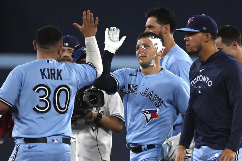 Daulton Varsho, de los Azulejos de Toronto, festeja tras ser embarrado de pastel durante el festejo por la victoria ante los Marineros de Seattle, el sábado 29 de abril de 2023 (Jon Blacker/The Canadian Press via AP)