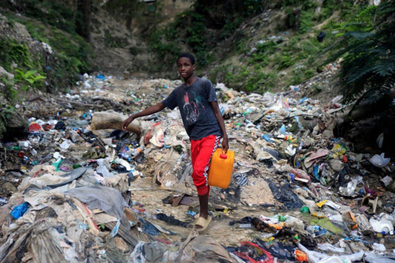 ARCHIVO - Un joven sin agua corriente en casa carga un bidón con agua recogida en un barranco, un día antes del Día Mundial del Agua, en Puerto Príncipe, Haití, el martes 21 de marzo de 2023. (AP Foto/Odelyn Joseph, Archivo)
