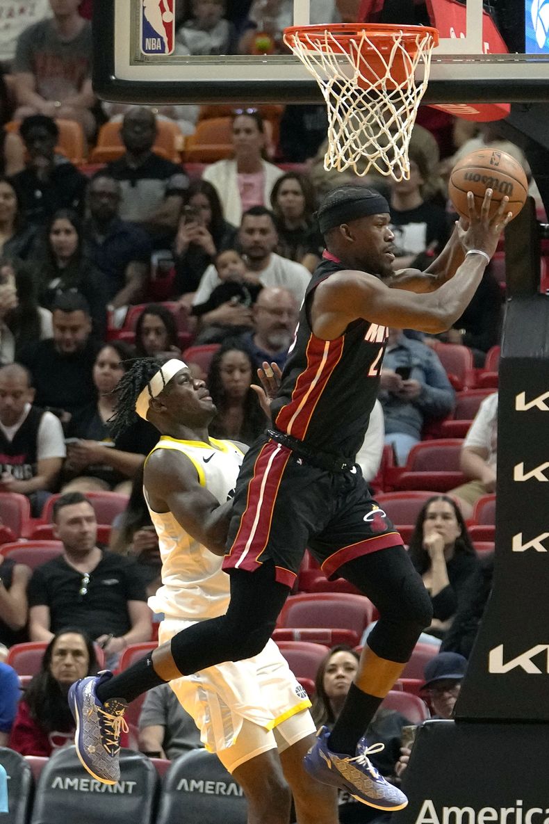 El alero del Heat de Miami, Jimmy Butler, a la derecha, busca pasar mientras el alero del Jazz de Utah, Taylor Hendricks, a la izquierda, defiende durante la segunda mitad del partido de baloncesto de la NBA, el sábado 2 de marzo de 2024, en Miami. (AP Foto/Lynne Sladky)