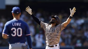 Fernando Tatis Jr., derecha, de los Padres de San Diego, alza los brazos después de conectar un sencillo productor de una carrera frente a los Rangers de Texas en la novena entrada del juego de béisbol, el domingo 30 de julio de 2023, en San Diego. (AP Foto/Derrick Tuskan)