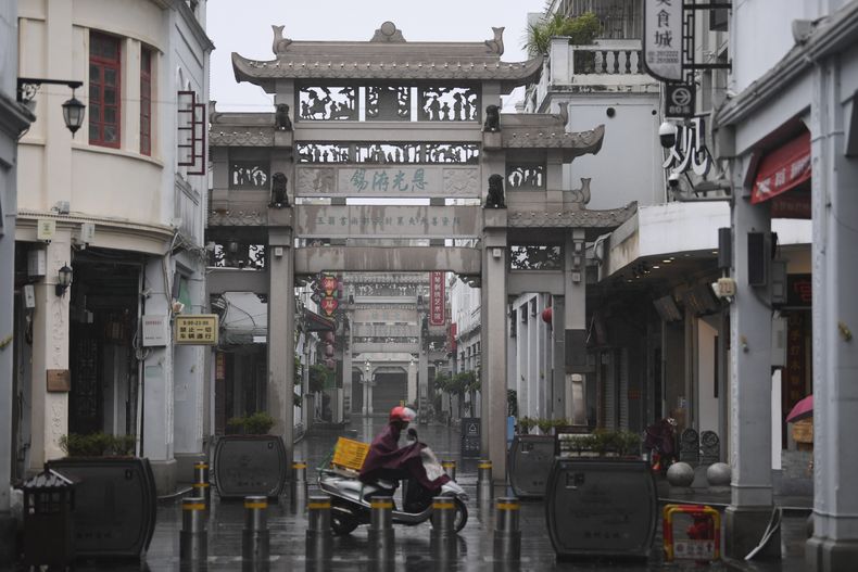 En esta imagen distribuida por la agencia noticiosa Xinhua, un motorista pasa por delante de una puerta tradicional con las calles mojadas, en la ciudad de Chaozhou, en la provincia de Guangdong, en el sur de China, el 5 de septiembre de 2023. (Deng Hua/Xinhua vía AP)