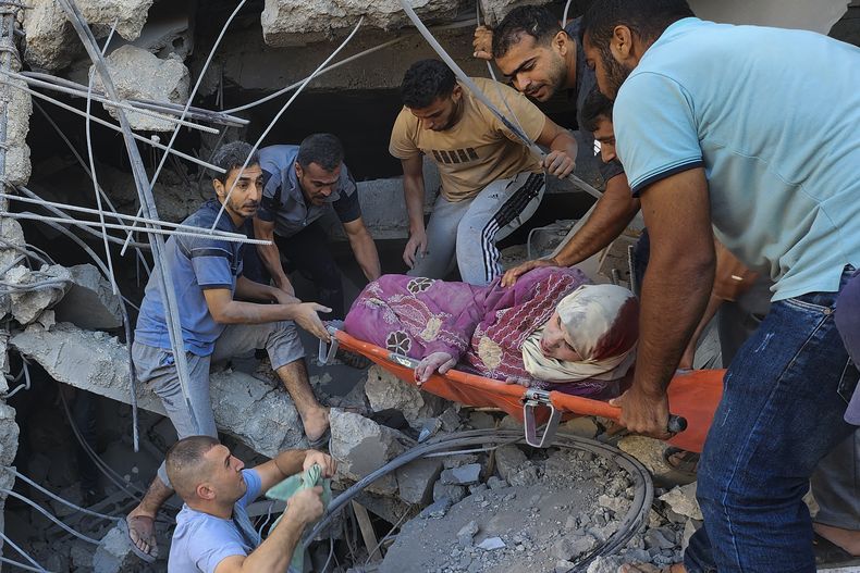 Palestinos rescatan a una mujer tras un ataque israelí contra edificios de la familia Abu Asad en Deir el Balah, en el sur de la Franja de Gaza, el sábado 21 de octubre 2023. (AP Foto/Hassan Eslaiah)