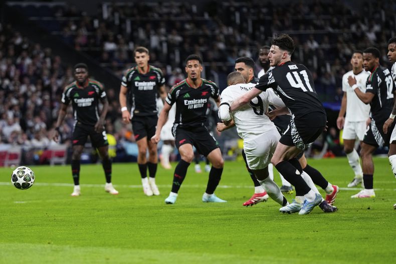 Declan Rice, del Arsenal a la derecha, agarra a Kylian Mbappé del Real Madrid en el área durante el partido de vuelta de los cuartos de final de la Liga de Campeones entre el Real Madrid y el Arsenal en el estadio Santiago Bernabéu en Madrid, el miércoles 16 de abril de 2025. (AP Foto/Manu Fernández)