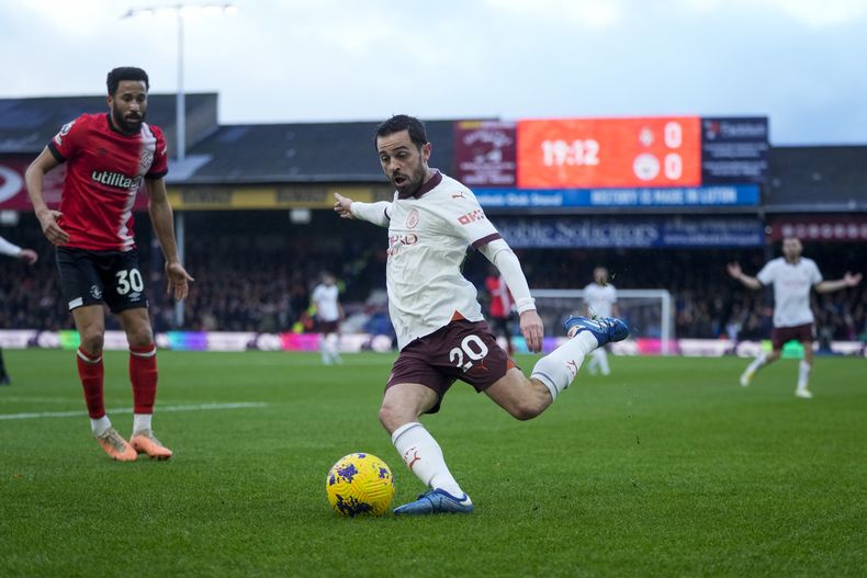 Bernardo Silva del Manchester City dispara el balón frente a Andros Townsend del Luton en el encuentro de la Liga Premier el domingo 10 de diciembre del 2023. (AP Foto/Kin Cheung)