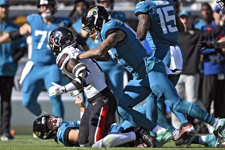 Evan Engram (17), tight end de los Jaguars de Jacksonville, se lanza sobre el linebacker Azeez Al-Shaair (0), de los Texans de Houston, después de que el defensivo golpeara de forma tardía al quarterback Trevor Lawrence (16) durante la primera mitad del juego de la NFL del domingo 1 de diciembre de 2024, en Jacksonville, Florida. (AP Foto/Phelan M. Ebenhack)