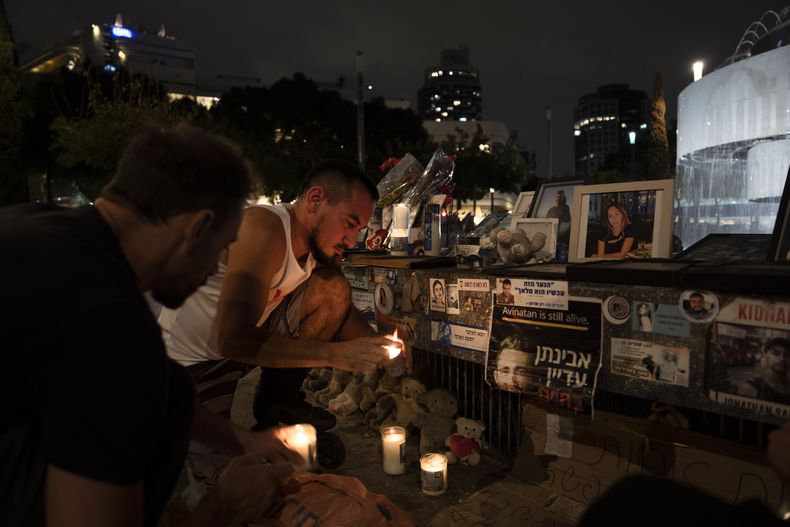 Gente encendiendo velas en un altar de recuerdo a las víctimas del ataque transfronterizo de Hamás del 7 de octubre contra Israel, la víspera del primer aniversario del ataque en Tel Aviv, Israel, el domingo 6 de octubre de 2024. (AP Foto/Oded Balilty)