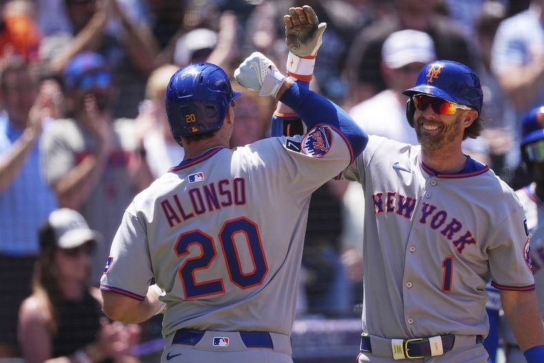 Jeff McNeil, derecha, de los Mets de Nueva York, felicita a su compañero de equipo Pete Alonso mientras regresa al dugout después de batear un cuadrangular de dos carreras frente al abridor de los Rockies de Colorado, Chase Dollander, en la tercera entrada del juego de béisbol de Grandes Ligas, el domingo 8 de junio de 2025, en Denver. (AP Foto/David Zalubowski)