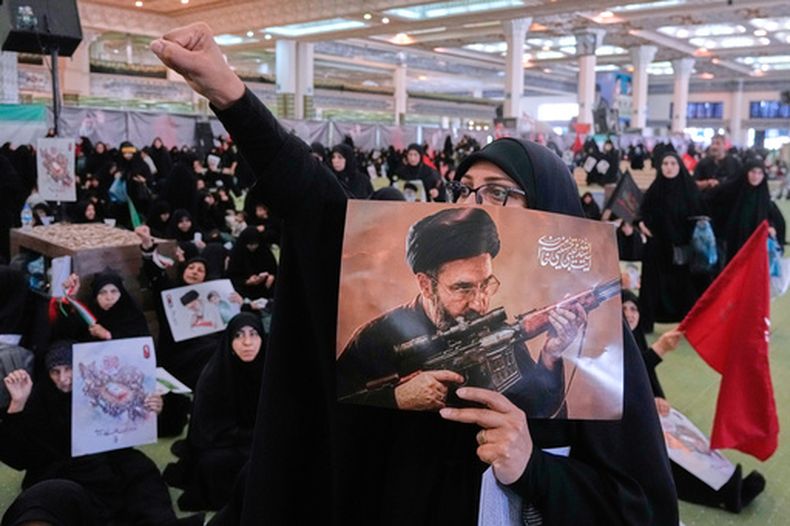 Una doliente corea un lema mientras sostiene un cartel con un dibujo del líder supremo de Irán, el ayatolá Moytabá Jamenei, en un funeral por el fallecido líder supremo Alí Jamenei, en la Gran Mezquita Imán Jomeini en Teherán, el martes 14 de julio de 2026. (AP Foto/Vahid Salemi)
