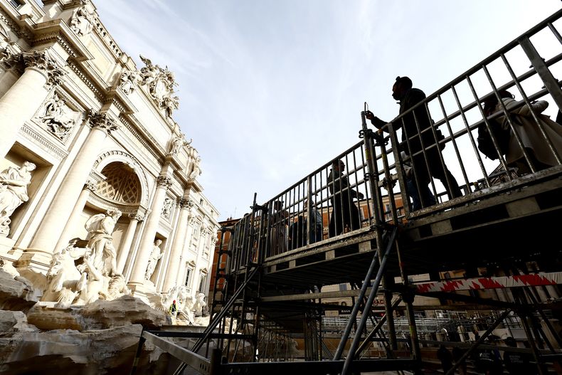 Personas caminan por una pasarela elevada que da acceso limitado a la Fuente de Trevi durante trabajos de mantenimiento en Roma, el sábado 9 de noviembre de 2024. (Cecilia Fabiano/LaPresse vía AP)