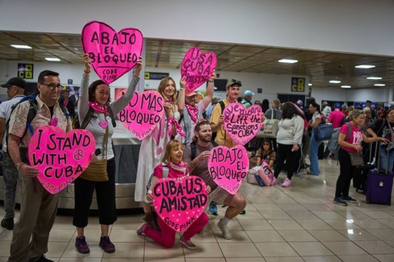 Activistas de CODEPINK, entre ellas la cofundadora Medea Benjamín, arrodillada en el centro, y otras personas sostienen pancartas como parte de la Nuestra América (Convoy) tras aterrizar en el aeropuerto de La Habana, Cuba, el viernes 20 de marzo de 2026. (Foto AP/Ramón Espinosa)