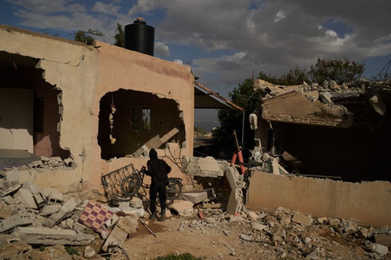 ARCHIVO - Un beduino lleva una bicicleta junto a casas que, según residentes locales, sufrieron graves daños el día anterior en un ataque de colonos israelíes en Al-Dyouk, en la zona de Al-Tahta, a las afueras de la ciudad cisjordana de Jericó, el 11 de febrero de 2026. (AP Foto/Leo Correa, Archivo)