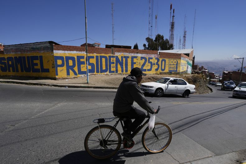 Un ciclista pasa junto a un mural que promueve al candidato presidencial Samuel Doria Medina en El Alto, Bolivia, el lunes 11 de agosto de 2025. (AP Foto/Juan Karita)