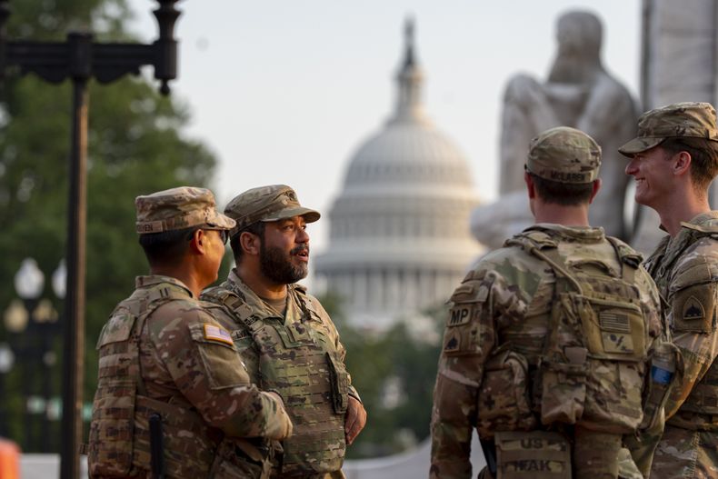 Soldados de la Guardia Nacional del Distrito de Columbia conversan en la Estación Union, con el Capitolio de Estados Unidos a sus espaldas, en Washington, el viernes 15 de agosto de 2025. (AP Foto/Alex Brandon)
