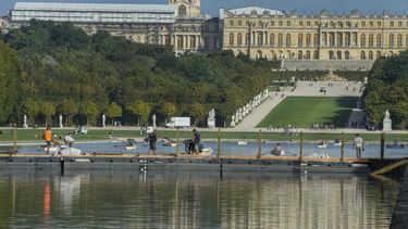 Trabajadores de construcción se paran en un puente que atraviesa el Gran Canal del Palacio de Versalles, el martes 22 de agosto de 2023 (AP Foto/Michel Euler)