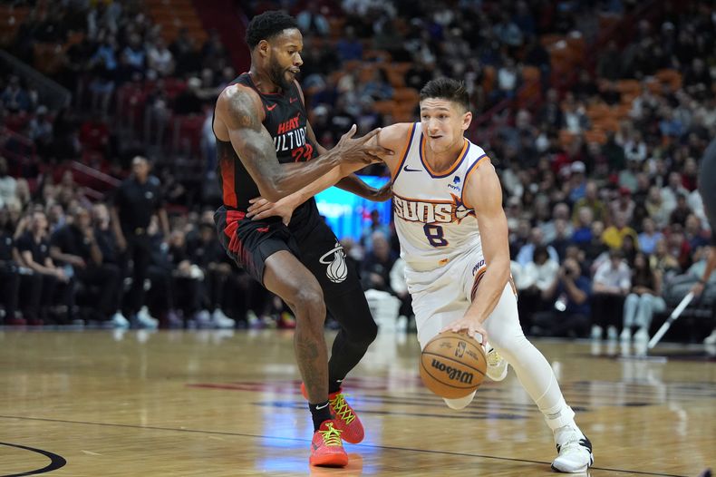 Grayson Allen (8), de los Suns de Phoenix, lleva el balón pasando sobre la marca de Haywood Highsmith (24), del Heat de Miami, durante la primera mitad del juego de baloncesto de la NBA, el lunes 29 de enero de 2024, en Miami. (AP Foto/Wilfredo Lee)