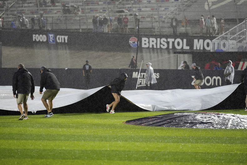 Miembros del equipo cubren el campo después de que se suspendiera el juego entre los Bravos de Atlanta y Rojos de Cincinnati en el Bristol Motor Speedway por lluvia el sábado 2 de agosto del 2025. (AP Foto/George Walker IV)