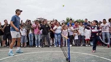 americateve | Un ni&ntilde;o devuelve una pelota de tenis al tenista espa&ntilde;ol Rafael Nadal, izquierda, en una visita de Nadal a un barrio pobre en Buenos Aires el martes, 19 de noviembre de 2013. (AP Photo/Natacha Pisarenko)