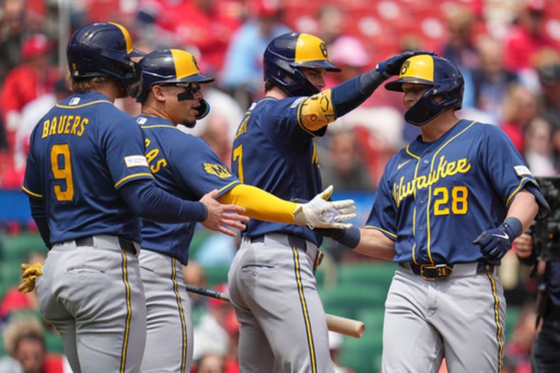 Andrew Vaughn (23), de los Cerveceros de Milwaukee, es felicitado por sus compañeros Jake Bauers (9), William Contreras y Tyler Black (7) después de batear un jonrón de tres carreras en la primera entrada del juego de béisbol de Grandes Ligas frente a los Cardenales de San Luis, el miércoles 6 de mayo de 2026, en San Luis. (AP Foto/Jeff Roberson)