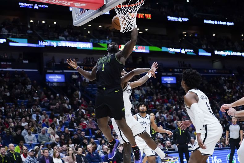 Zion Williamson, alero de los Pelicans de Nueva Orleáns, salta hacia la canasta frente a Royce ONeale, de los Nets de Brooklyn, en la segunda mitad del partido del martes 2 de enero de 2024 (AP Foto/Gerald Herbert)