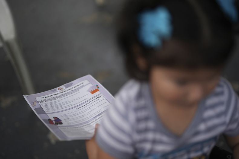 Una niña nacida en Estados Unidos se sienta en las piernas de su madre mientras Nora Sandigo, que dirige una organización sin fines de lucro dedicada a apoyar a las familias de inmigrantes, explica los derechos legales de los migrantes y las opciones que tienen para preparar a sus familias en caso de que uno de los padres sea detenido o deportado, el viernes 17 de enero de 2025, en Homestead, Florida. (AP Foto/Rebecca Blackwell)